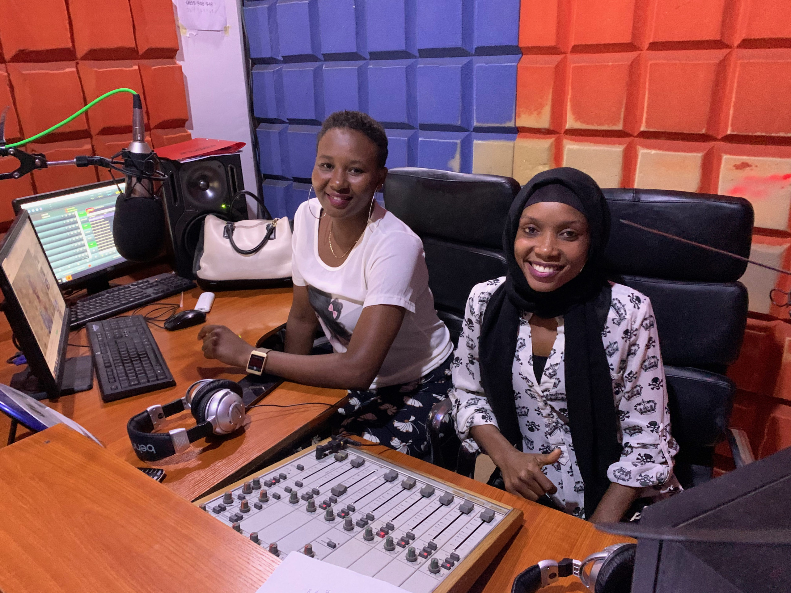 Kaksi tansanialaista naista hymyilee radiostudiossa