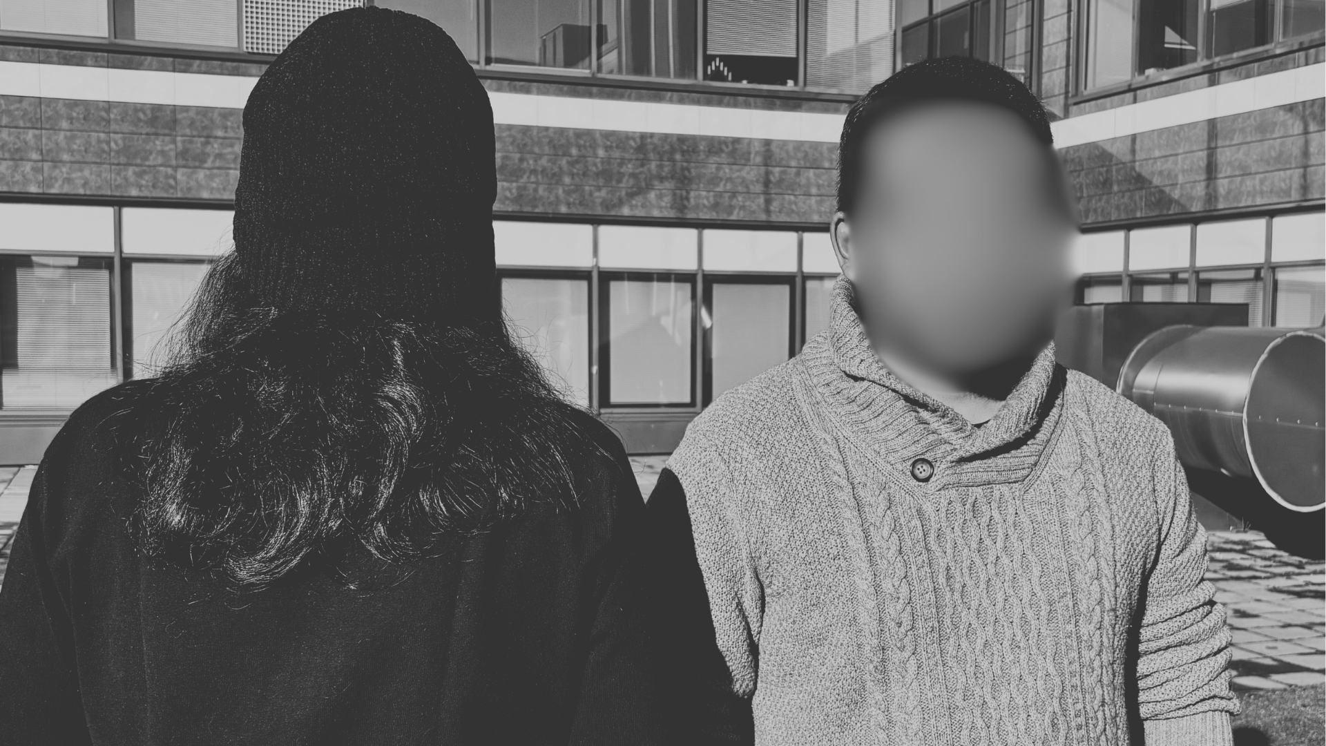Kaksi henkilöä seisoo. Toinen on selin kameraan ja toisen kasvot on blurrattu.