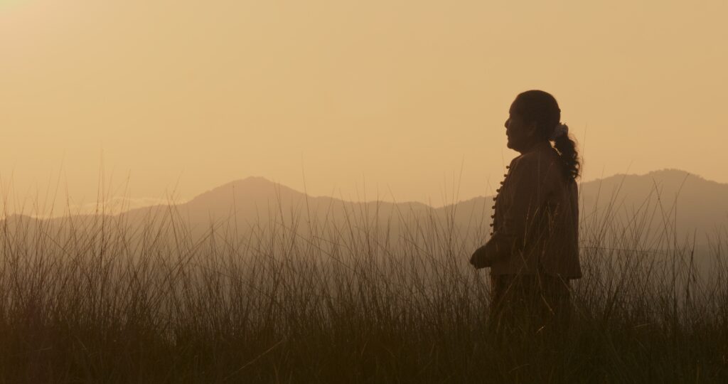 Song of Souls elokuvan promokuva. Nainen seisoo keltaisessa auringonlaskussa ja taustalla on tummia vuoria.